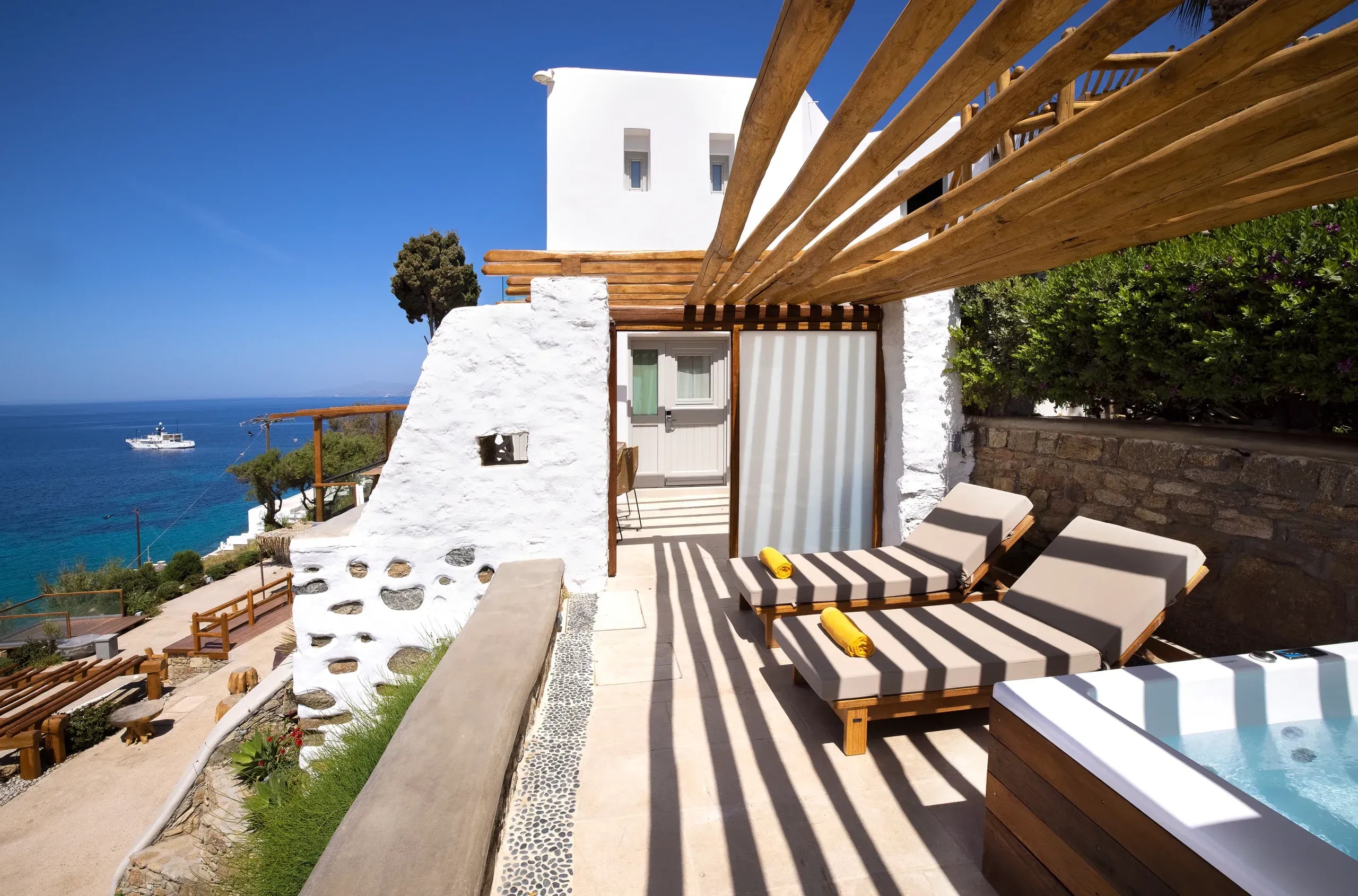 Timber pergola over the sun terrace at Legacy Mykonos, with the Aegean beyond
