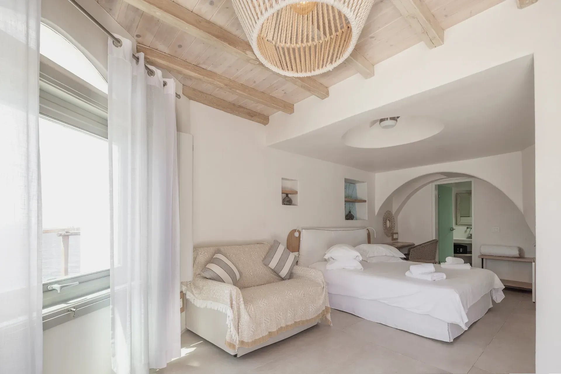 Seating and bed under the timber beam ceiling with a rattan pendant light