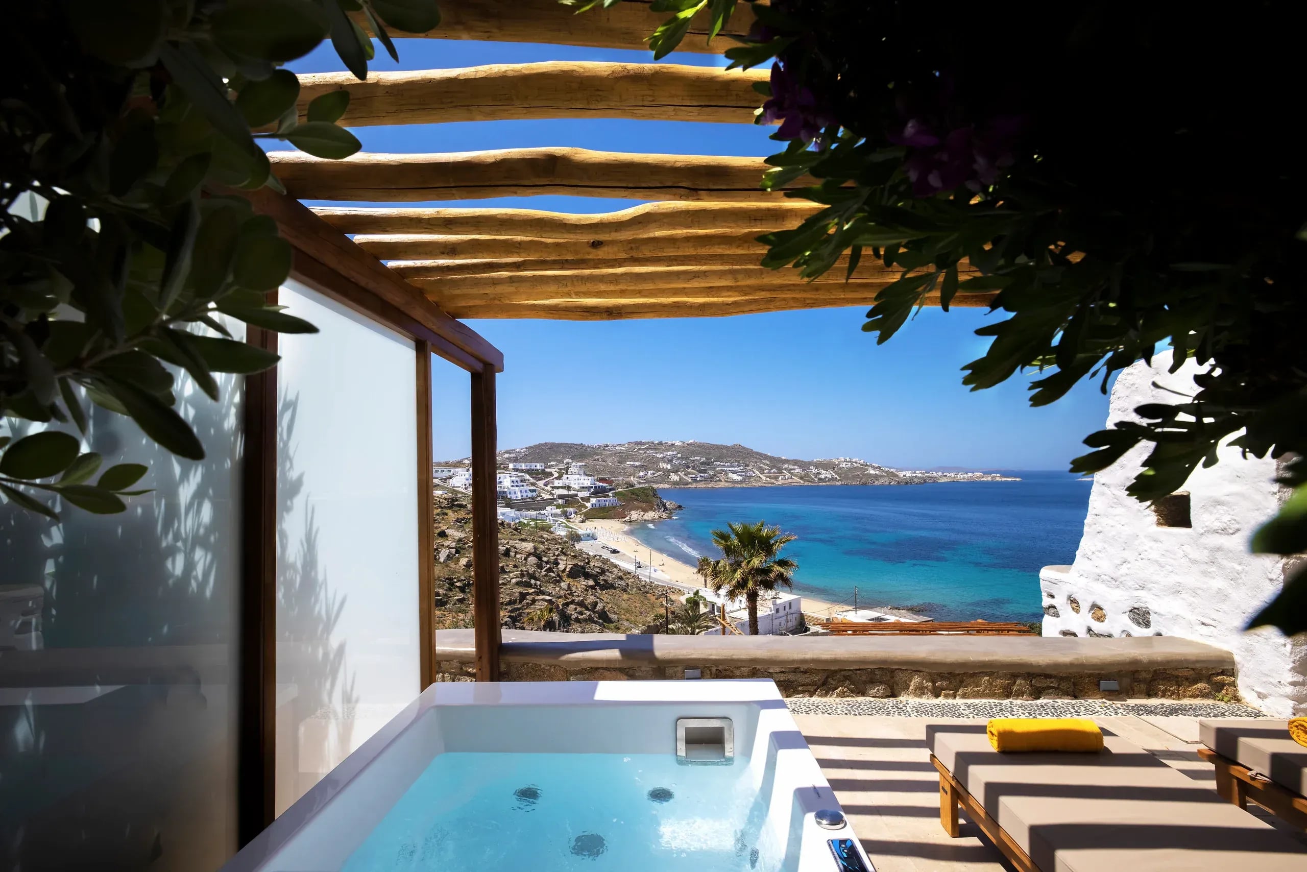 A timber sun deck and outdoor hot tub under the pergola, open to the Aegean
